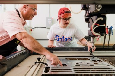 instructor assisting student with large machine