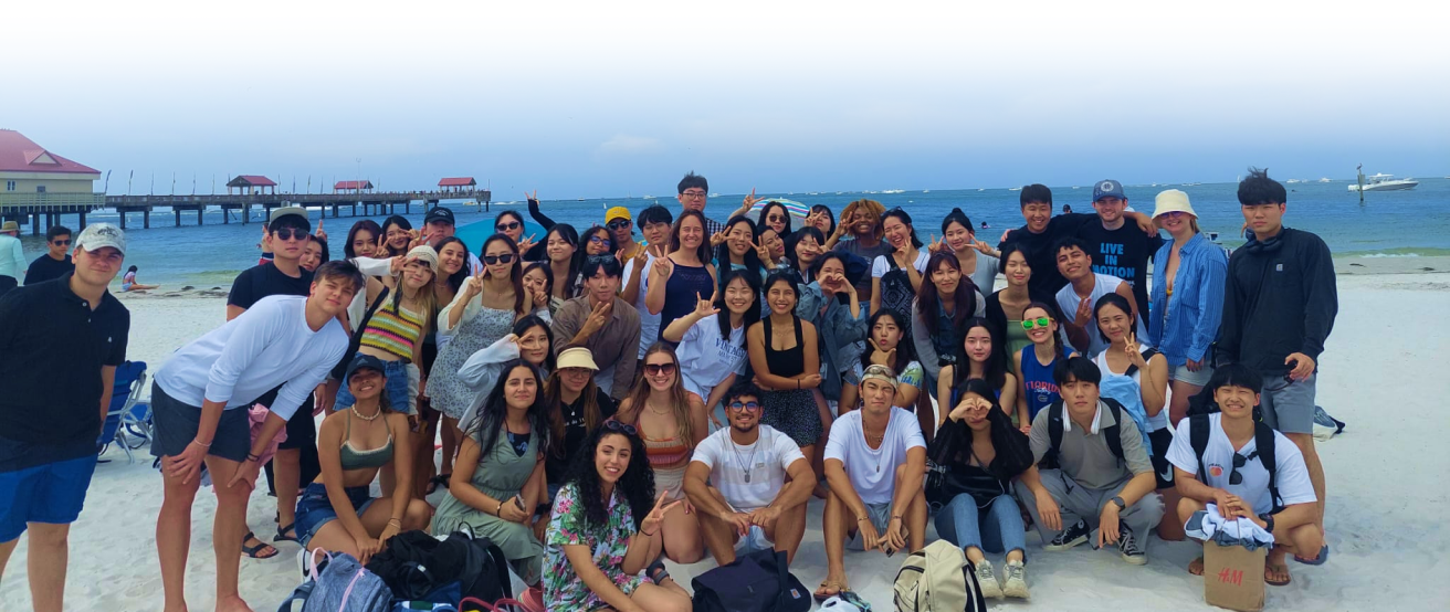 large group of young people pose for photo on beach